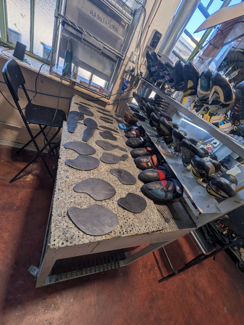 Photo of workbench with climbing shoes and soles set up for work.